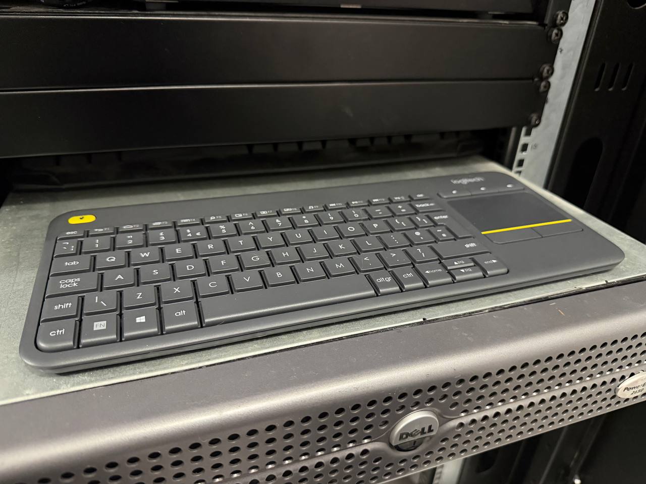 Logitech K400 Plus wireless keyboard sitting on top of a Dell PowerEdge server in a rack cabinet, showing the integrated trackpad and compact layout
